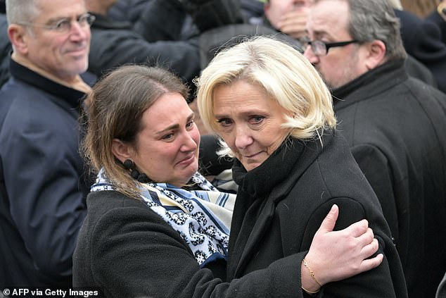 Marine Le Pen was comforted today by a fellow mourner outside the service in Paris