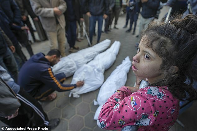 A girl watches as Mohammad Eid mourns his cousin Dima, along with her uncle and grandfather, who were killed in an Israeli airstrike on Saturday, during their funeral in Deir al-Balah, central Gaza Strip, Sunday