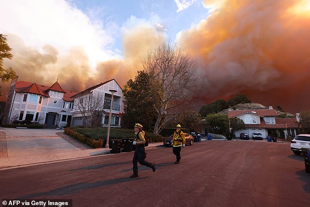 Firefighters run as a wildfire burns in Pacific Palisades, California