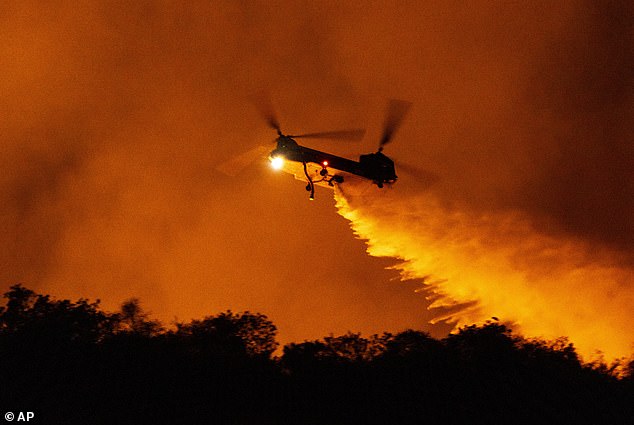 A helicopter drops water on the Palisades fire in Mandeville Canyon on Saturday