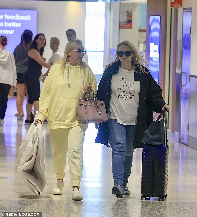 Rolling past her carry-on, Rebel kept her face free of makeup as she let her blonde locks fall down her back in their natural curl pattern.