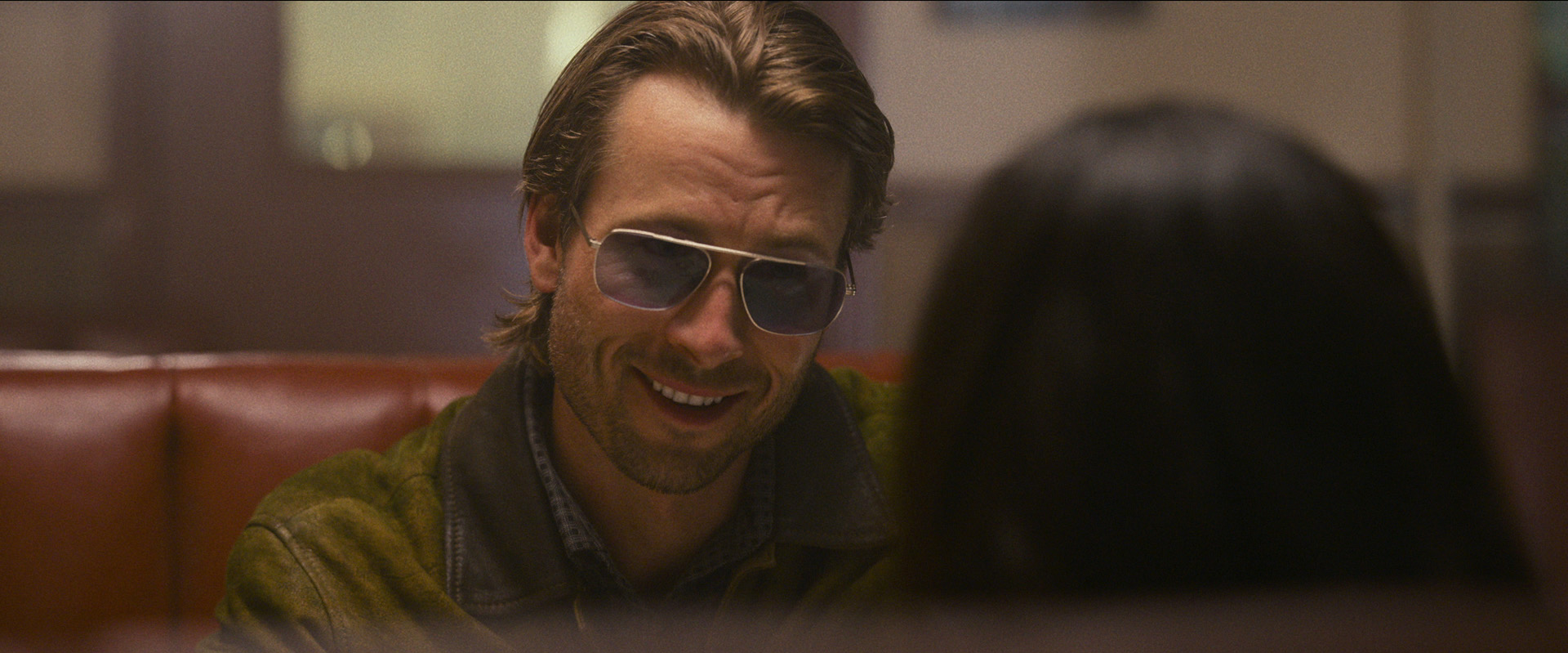 Glen Powell grins friendly in shades in Hit Man