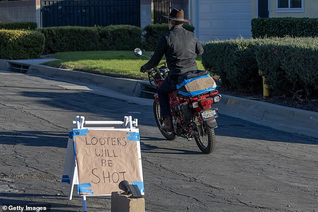 Pictured: A man on a motorcycle passes a sign that reads 