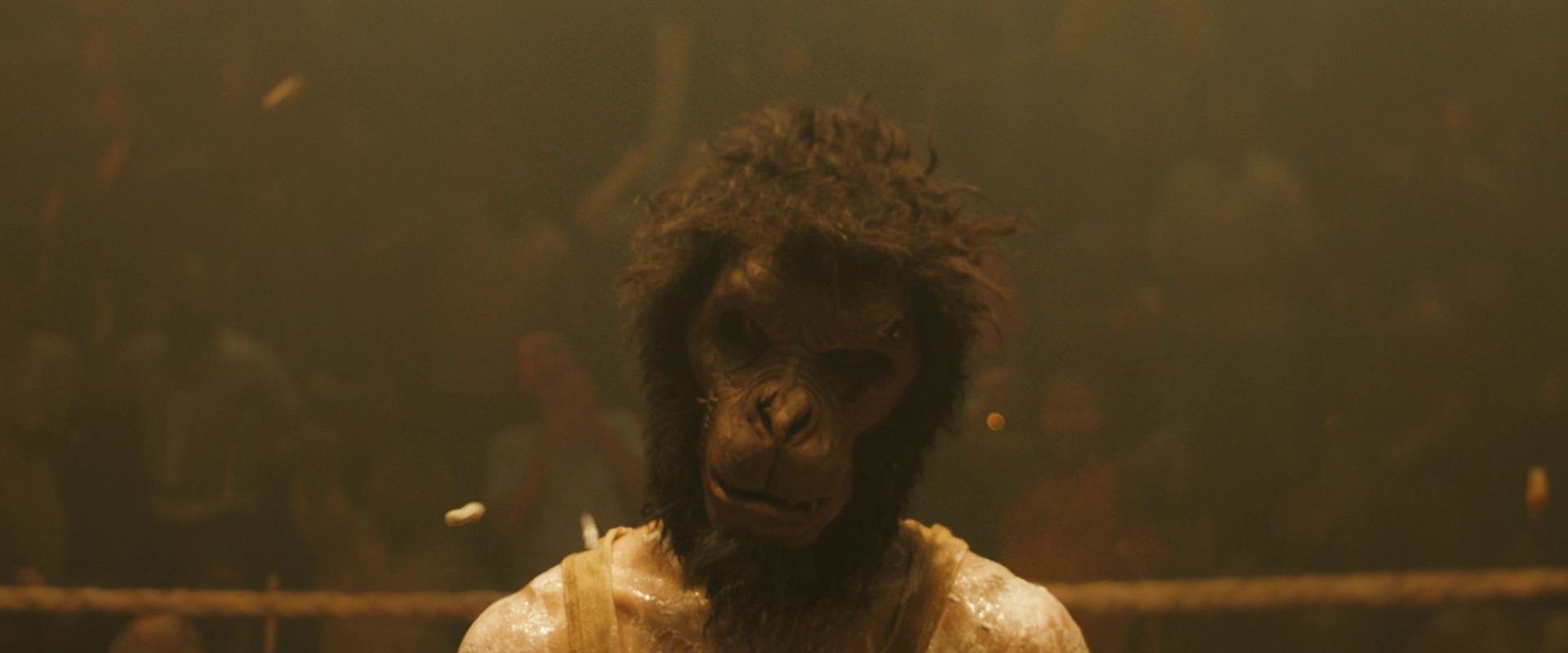 A man in a monkey mask looks at the camera in Monkey Man