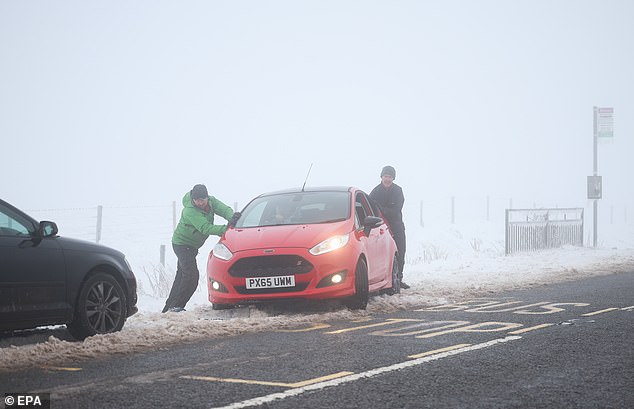 The warning comes as Britain experiences its coldest night of the winter season yet. Pictured: Members of the Derbyshire Mountain Rescue team help a motorist amid whiteout conditions on the Snake Pass on Thursday