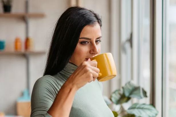 A young woman sitting alone in a cozy apartment, enjoying her morning coffee
