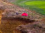 That's no place to pitch your tent! 'Idiot' climbs fence and ignores warning signs to set up camp on edge of crumbling 150-foot coastal cliff