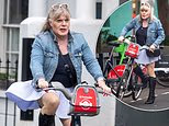 Suzy Eddie Izzard, 64, wears a pleated mini skirt and sky-high knee-high boots as she cycles through Notting Hill without a helmet